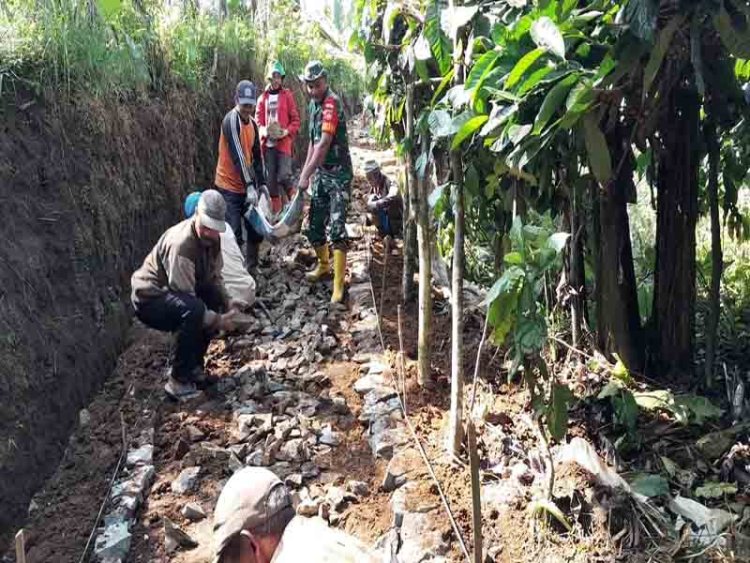 Babinsa Koramil 04/Karangkobar Bersama Warga Kerja Bakti Pembangunan Makadam Jalan Usaha Tani