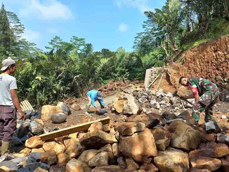 Babinsa Koramil 04/Karangkobar Bantu Warga Pecahkan Batu Pembangunan Pondasi Musollah